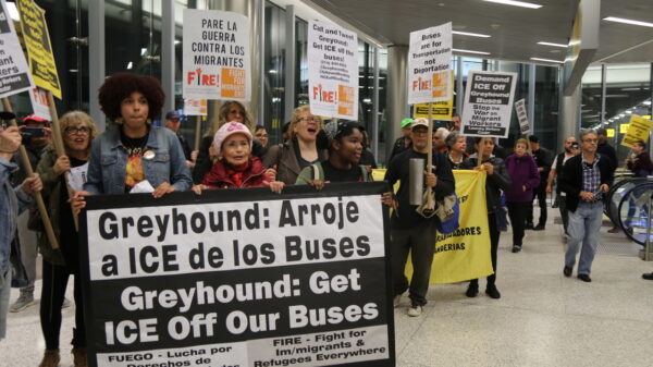 Person holding a protest sign in a Greyhound Bus Terminal
