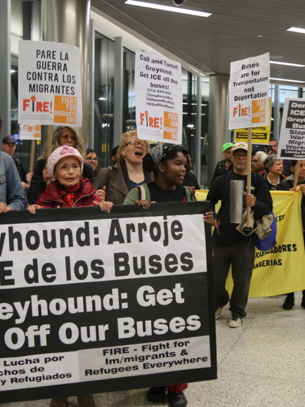 Person holding a protest sign in a Greyhound Bus Terminal