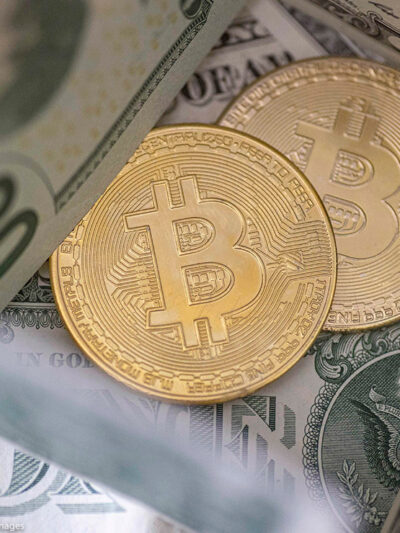 Two bitcoins on top of a pile of cash.
