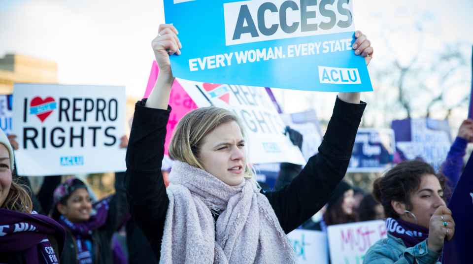 photo of a woman holding up a sign that reads, "every woman every state"