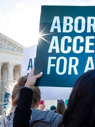 Person holding a sign that reads, “Abortion access for all.”