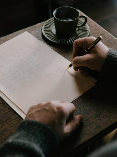 person writing a letter in a coffee shop