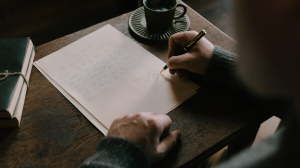 person writing a letter in a coffee shop