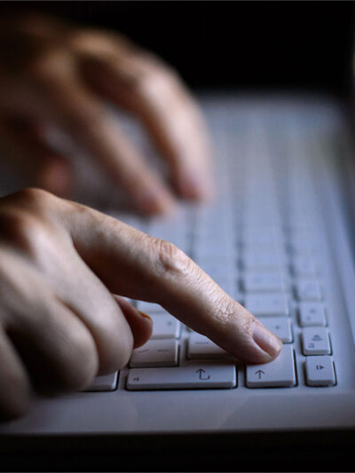 A person using a laptop with just their fingers showing.