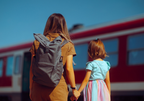 An image of a woman wearing a backpack holding the hand of a child.