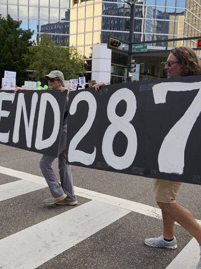 People in Florida carry a sign calling for an end to 287(g).