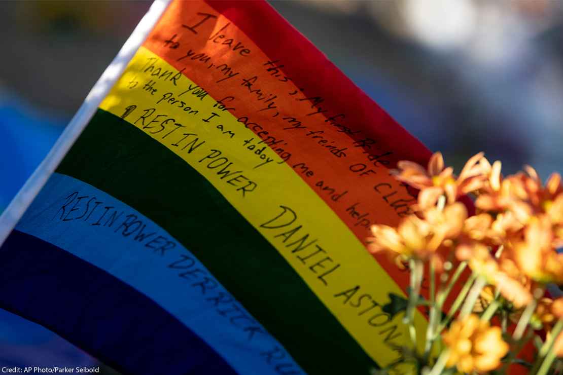 A waving rainbow flag reading "Rest In Power Daniel Aston" sits at the memorial created outside of Club Q.