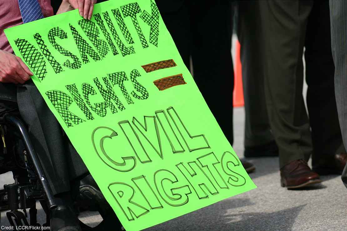 A wheelchair user holding a sign with the text "Disability rights = civil rights."