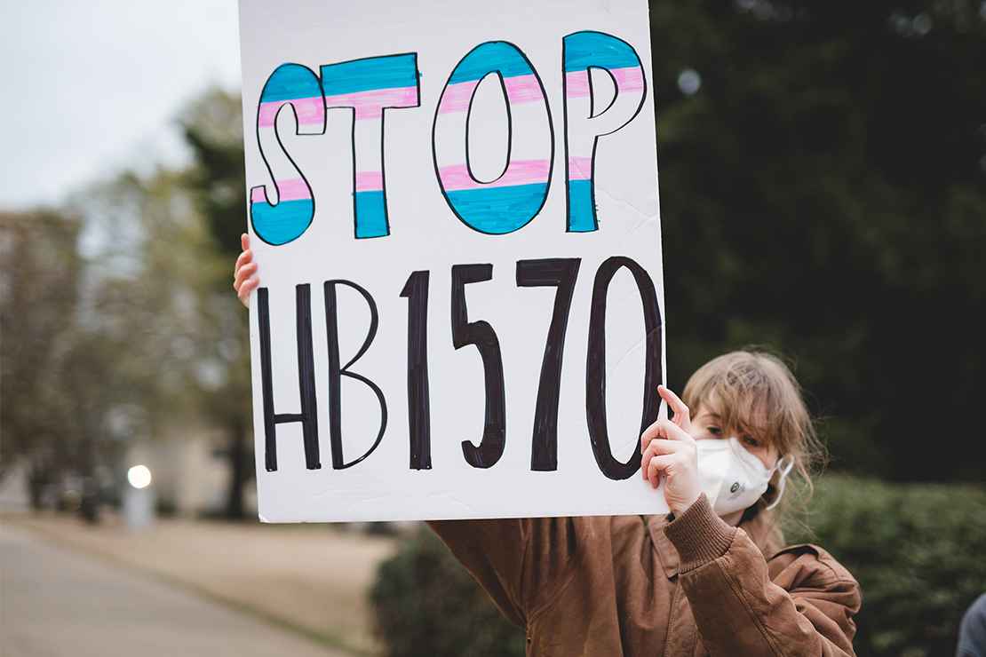 A demonstrator holding a sign with the text "Stop HB1570."