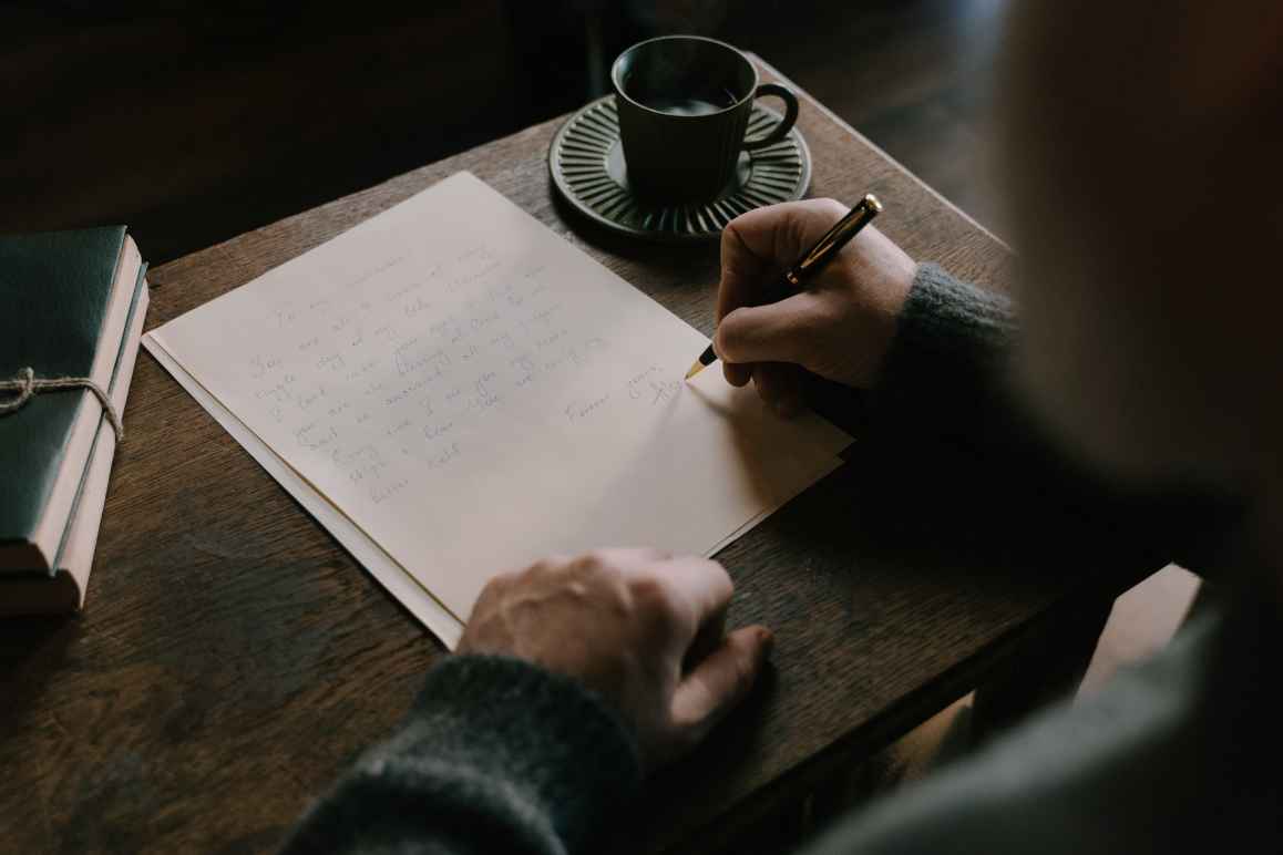 person writing a letter in a coffee shop
