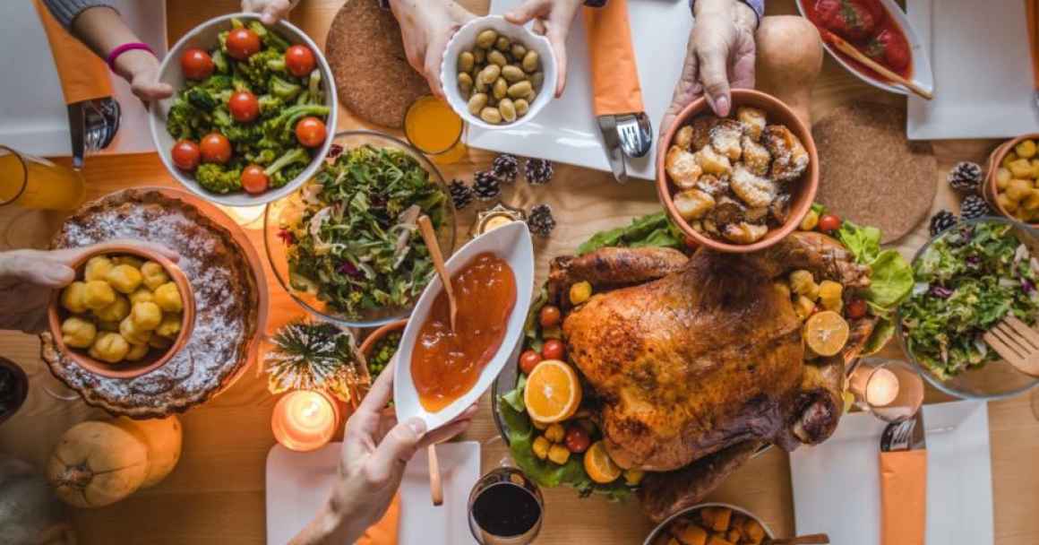 holiday dinner table with hands passing food