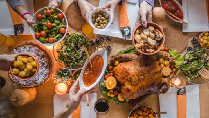 holiday dinner table with hands passing food