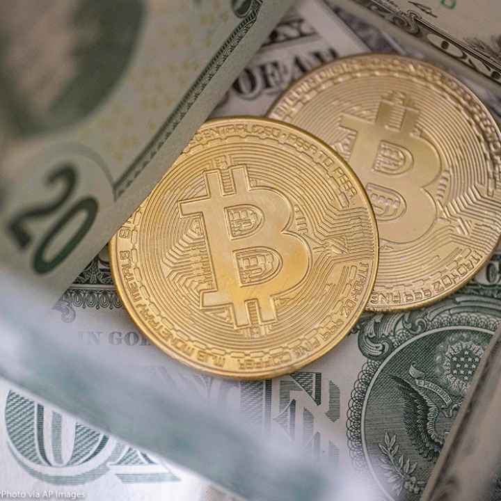 Two bitcoins on top of a pile of cash.