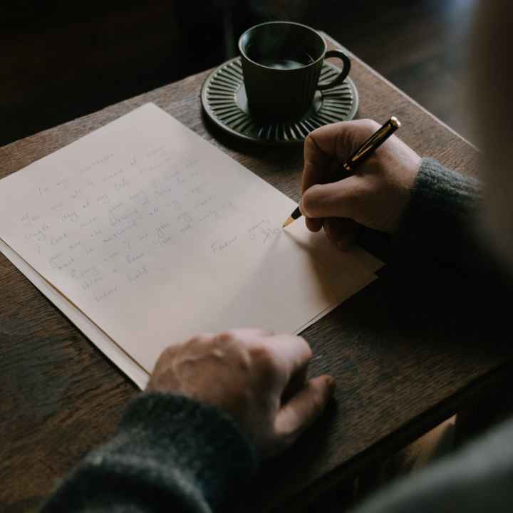 person writing a letter in a coffee shop