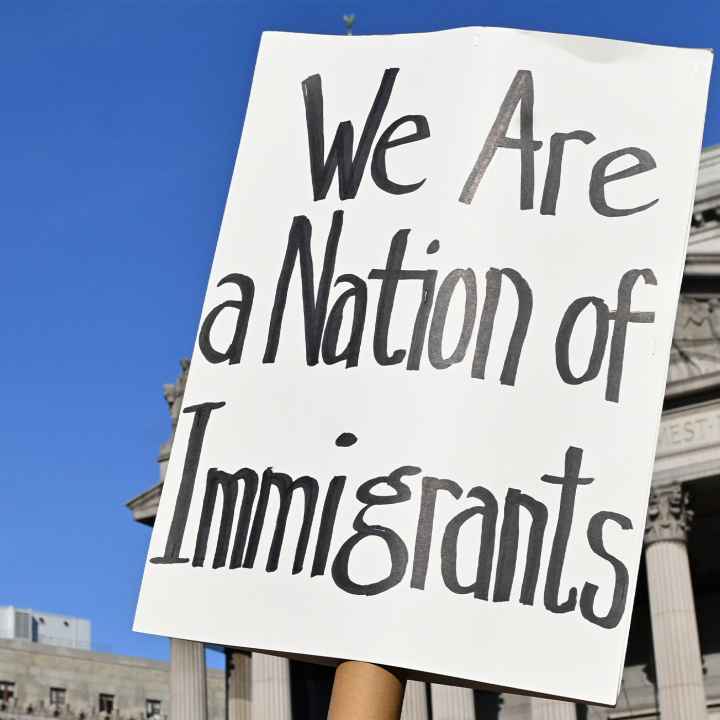 Two signs are held up during the May Day March In Manhattan, New York on May 1, 2025. The largest of the signs is in the foreground and reads"We Are a Nation of Immigrants," while the smaller in the background reads, " WE ARE ALL (EXCEPT NATIVE...